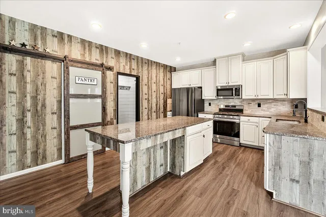 a kitchen with stainless steel appliances granite countertop a refrigerator a stove top oven a sink and cabinets