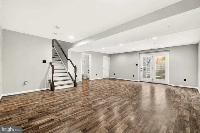 a view of an empty room with wooden floor and stairs