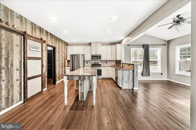 a kitchen with stainless steel appliances a refrigerator a stove top oven and wooden floors