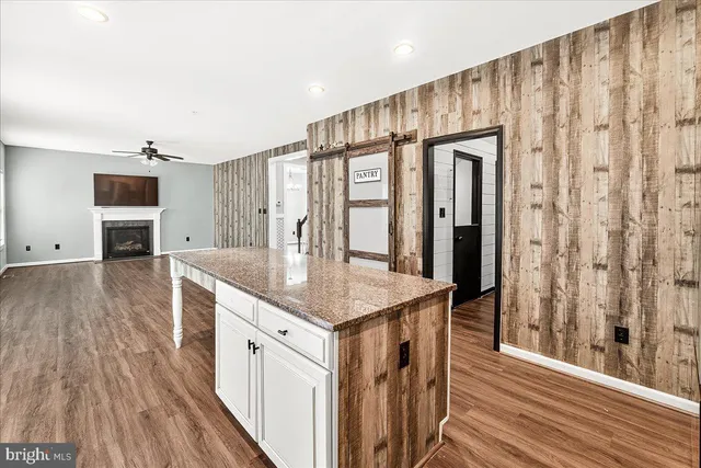 a kitchen with stainless steel appliances granite countertop a refrigerator a sink and wooden floors