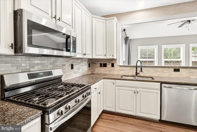 a kitchen with stainless steel appliances granite countertop a stove a sink and a microwave