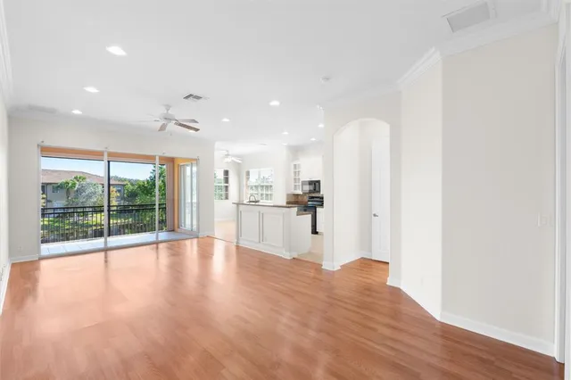 a view of empty room with wooden floor and fan