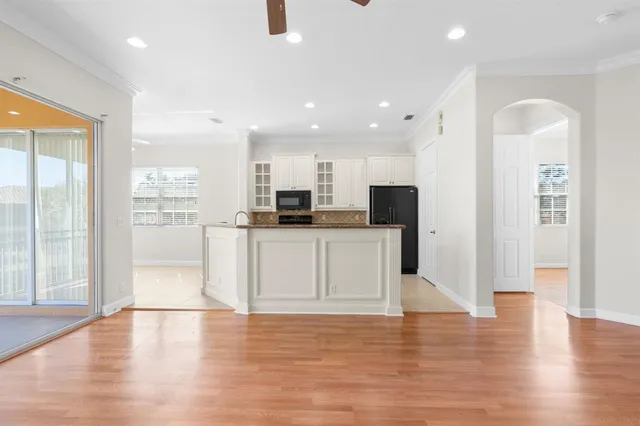 an empty room with wooden floor and kitchen view