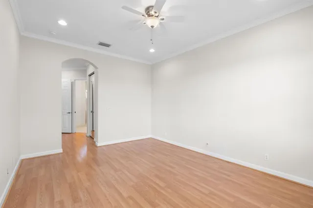 an empty room with wooden floor and a ceiling fan