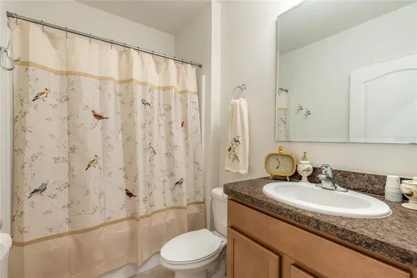 a bathroom with a granite countertop sink a toilet and shower