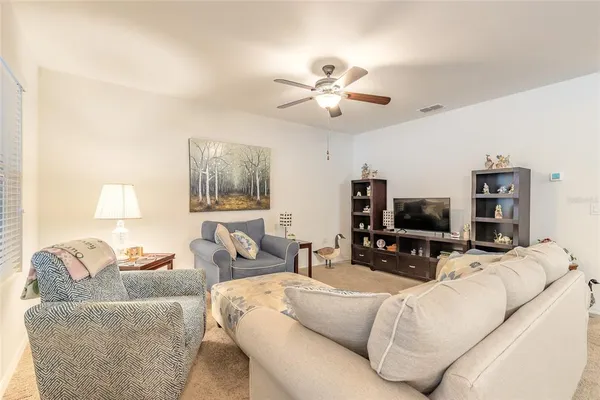 a living room with furniture a ceiling fan and a flat screen tv