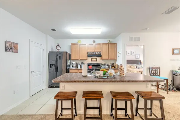 a kitchen with stainless steel appliances granite countertop a dining table chairs and refrigerator