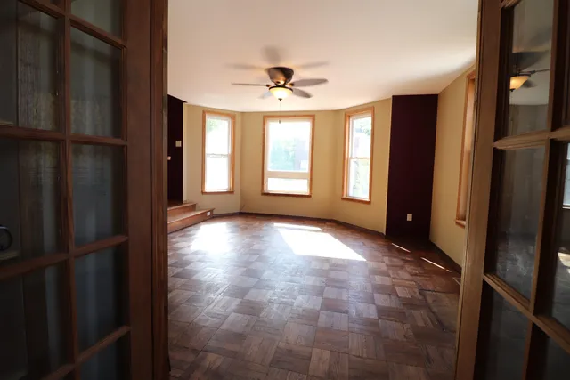 a view of empty room with wooden floor and fan