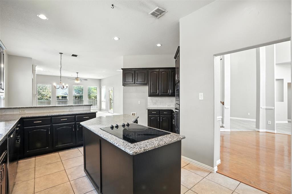 8220 Holliday Road Lantana, TX 76226 - Photo 14 of 40 Kitchen featuring an island cooktop, dark wood cabinetry, granite countertops, tile flooring, and a stone-finish backsplash