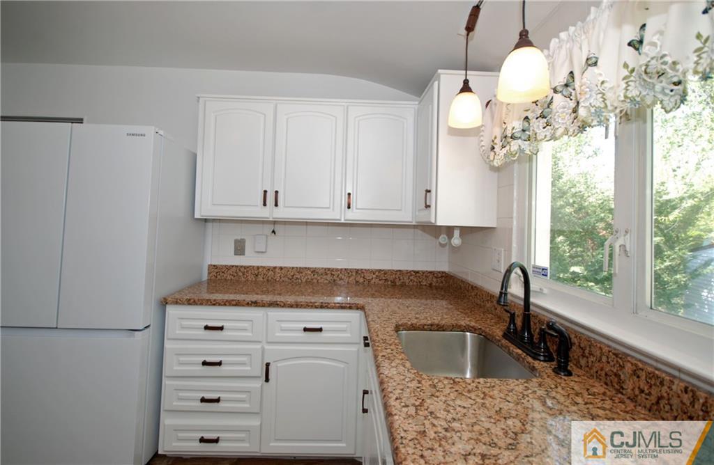 25 Barlow Road Edison, NJ 08817 - Photo 10 of 27 a kitchen with stainless steel appliances granite countertop a sink dishwasher and white cabinets with wooden floor