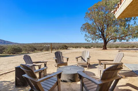 a view of a patio with table and chairs under an umbrella with a barbeque grill and couches