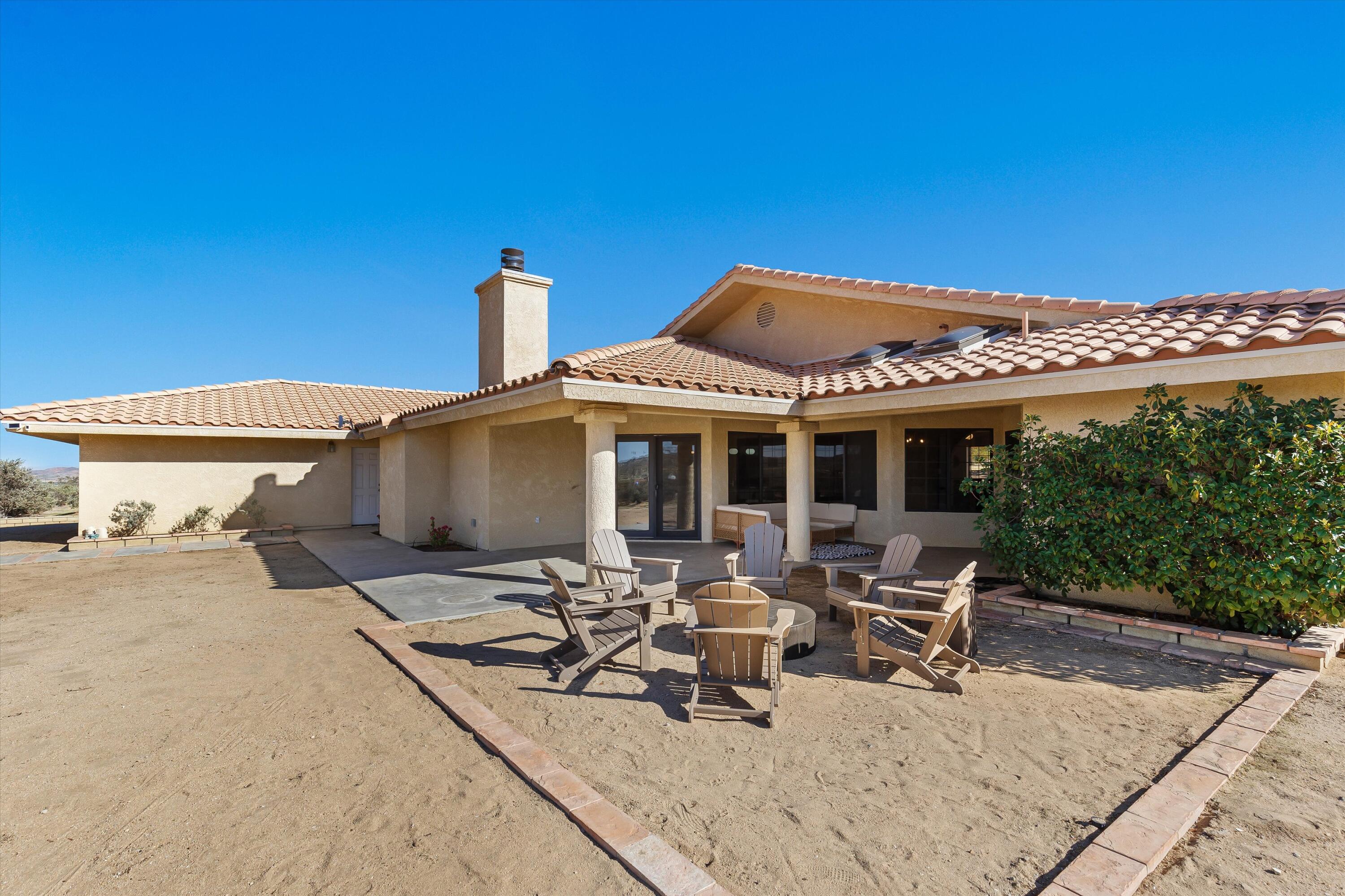 62850 Dennis Avenue Joshua Tree, CA 92252 - Photo 12 of 39 a view of a patio with table and chairs under an umbrella with a barbeque grill and couches