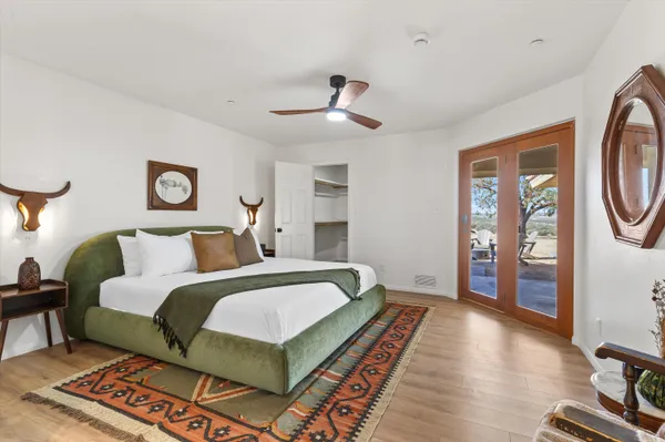 a spacious bedroom with a bed a mirror and a lamp on a bookshelf