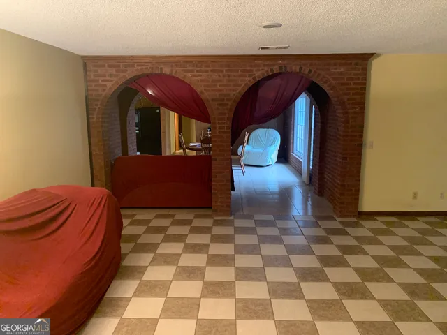 a living room with a black white checkered floor with a gaming machine and dining table