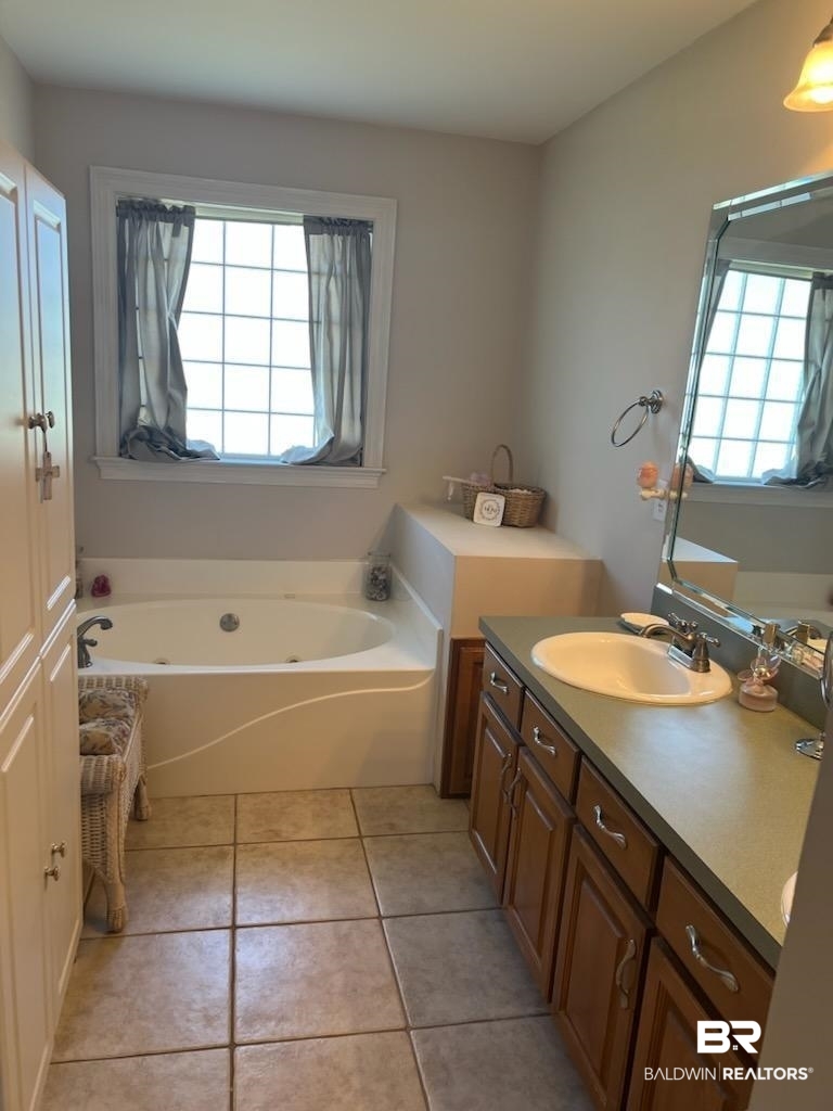 16311 Old Brady Road Bay Minette, AL 36507 - Photo 24 of 38 Bathroom featuring a built-in tub with a window, a vanity with a surface-mounted sink, wood-finish cabinetry, and tiled flooring