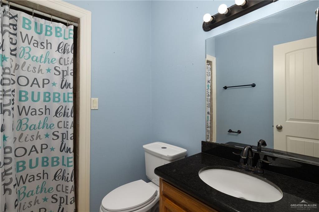 504 Orchard Court Weslaco, TX 78596 - Photo 18 of 24 a bathroom with a granite countertop toilet sink and mirror