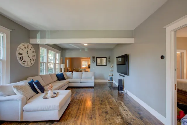 a living room with furniture a clock tv and a window