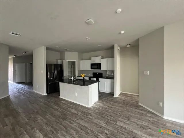a large kitchen with kitchen island a sink wooden floor and stainless steel appliances