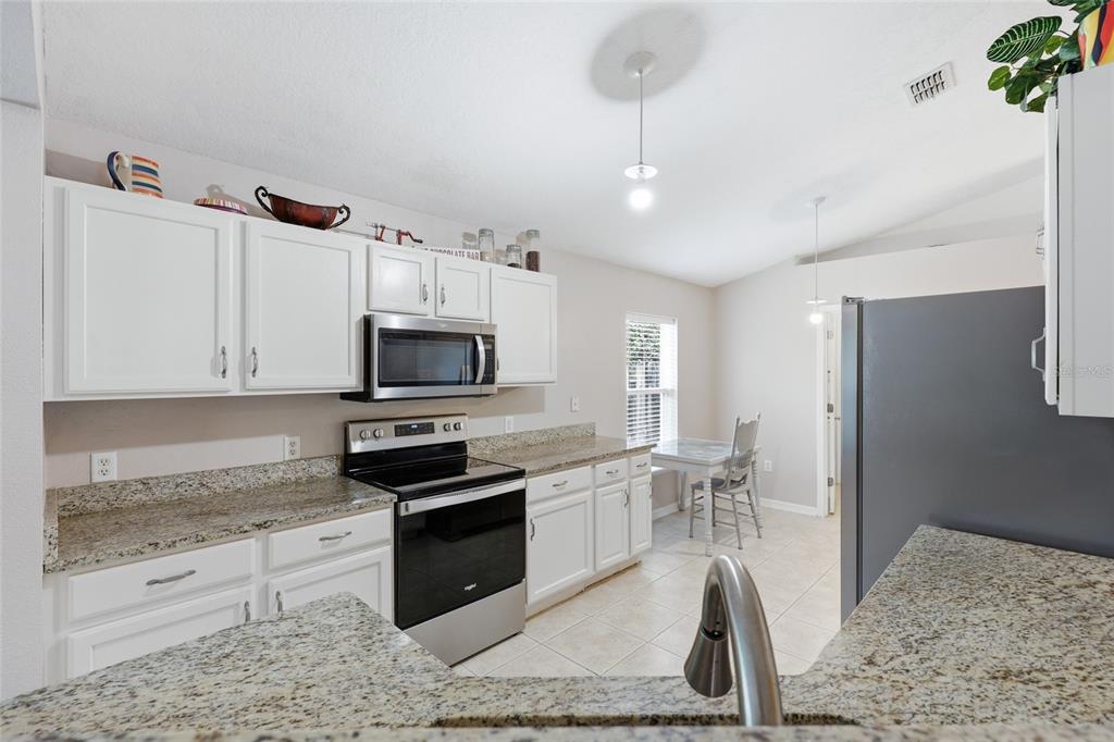 23152 Northwest 11th Road Newberry, FL 32669 - Photo 11 of 31 a kitchen with granite countertop a stove a sink and a refrigerator