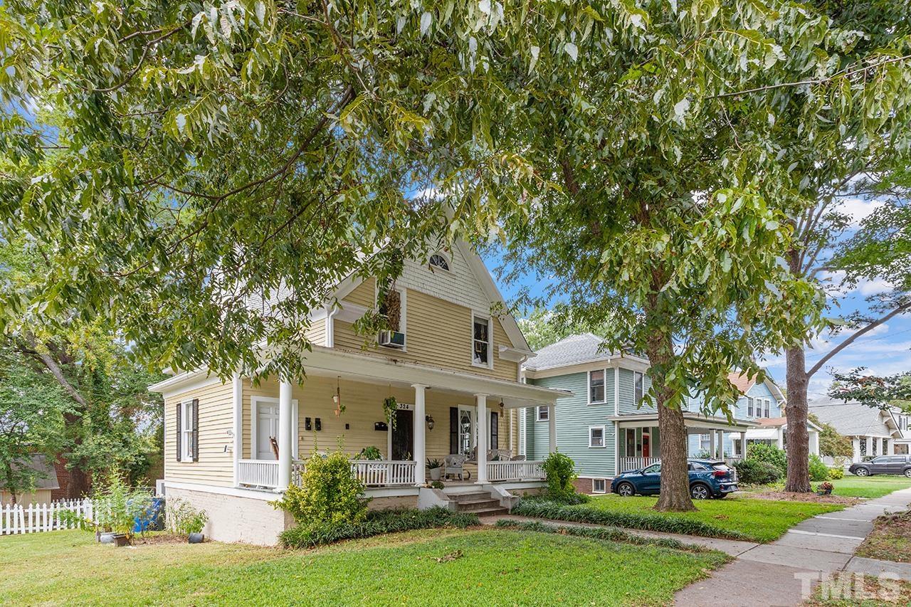 a front view of a house with a garden and trees