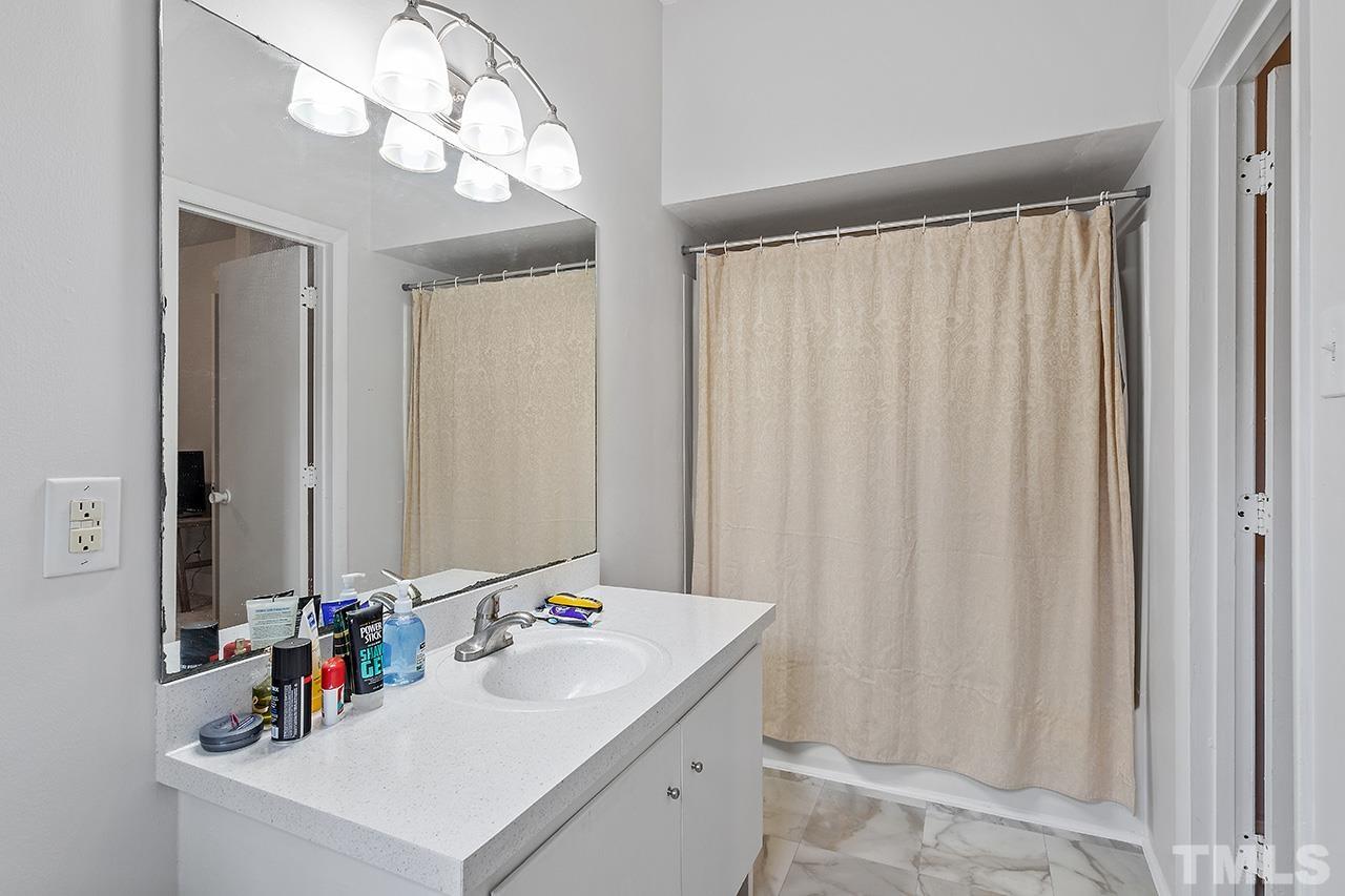 324 Cutler Street Raleigh, NC 27603 - Photo 32 of 34 a bathroom with a sink a mirror and a shower curtain