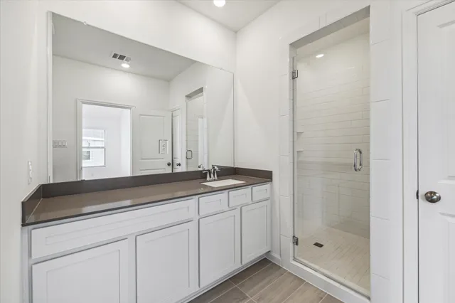 a bathroom with a granite countertop sink a mirror and a shower