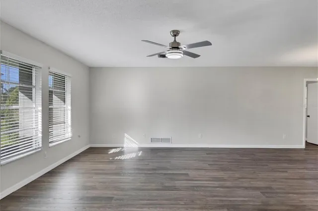 a view of empty room with wooden floor and fan