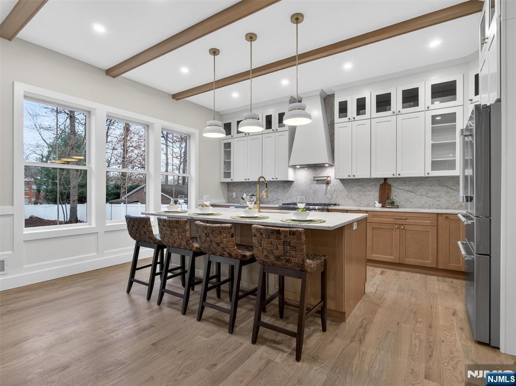 61 Beech Street Ramsey, NJ 07446 - Photo 11 of 41 a large white kitchen with granite countertop a stove a sink a dining table and chairs with wooden floor