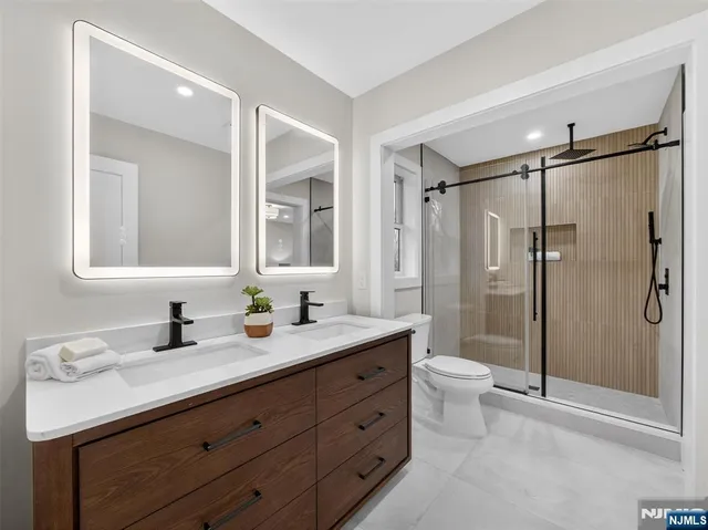 a bathroom with a double vanity sink toilet mirror and shower