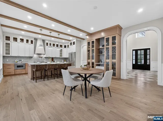 a dining hall with stainless steel appliances granite countertop a table and chairs with wooden floor