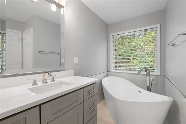 a bathroom with a white tub a sink and window
