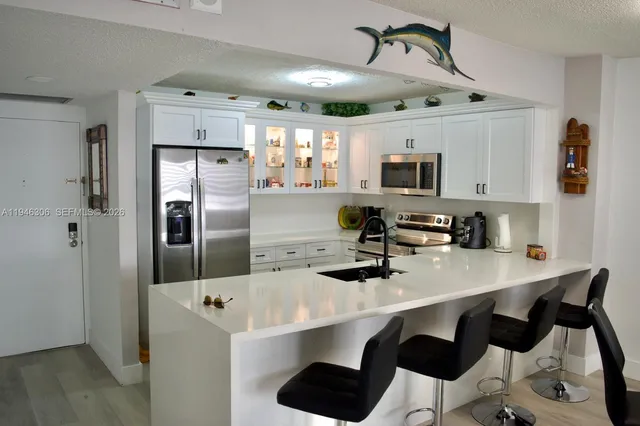 a kitchen with stainless steel appliances a refrigerator a stove a sink dishwasher and white cabinets with wooden floor