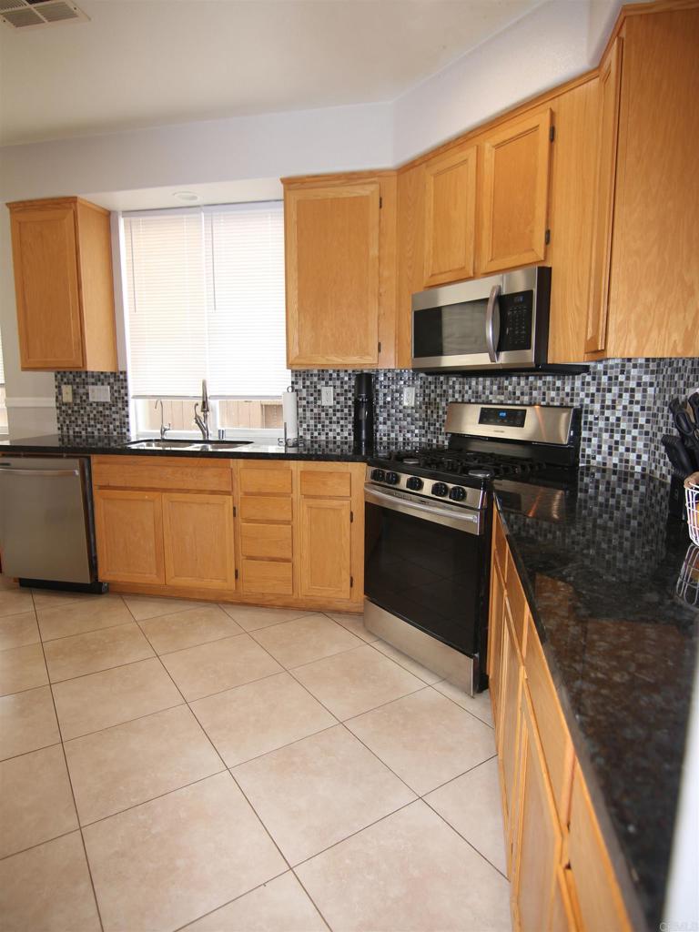 445 Poets Square Fallbrook, CA 92028 - Photo 6 of 37 a kitchen with stainless steel appliances granite countertop a stove a sink and a microwave