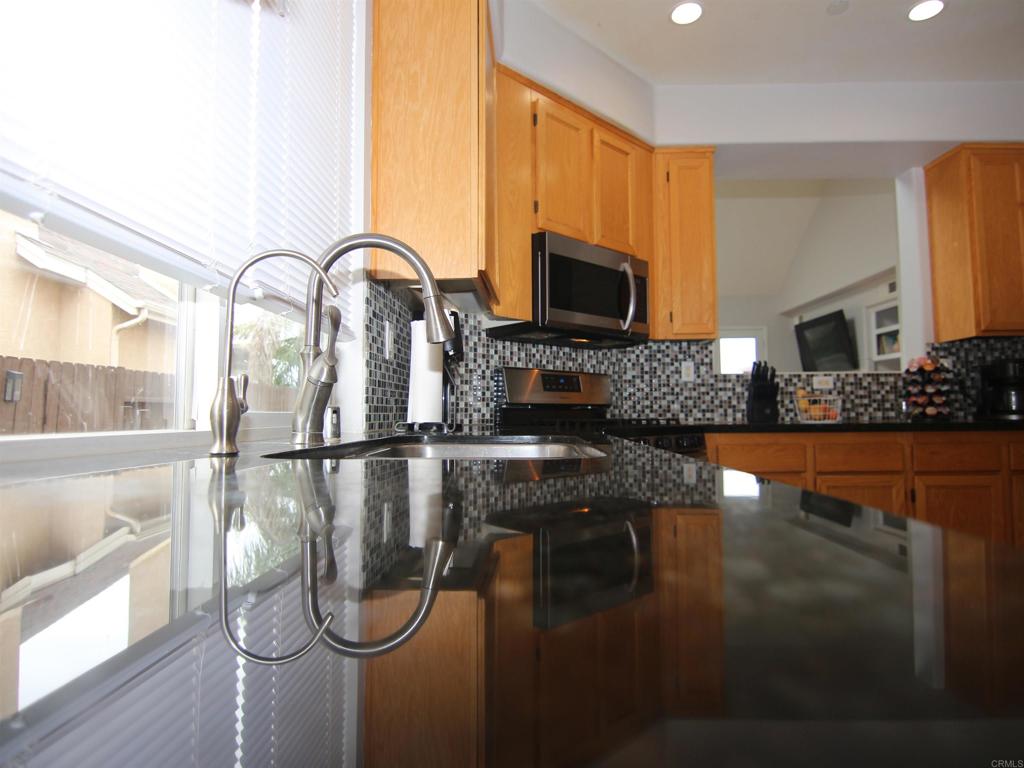 445 Poets Square Fallbrook, CA 92028 - Photo 9 of 37 a kitchen with stainless steel appliances granite countertop a stove a sink and a microwave