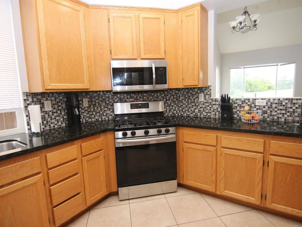 445 Poets Square Fallbrook, CA 92028 - Photo 10 of 37 a kitchen with stainless steel appliances granite countertop a sink and a microwave