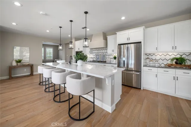 a kitchen with stainless steel appliances a dining table chairs a sink and cabinets