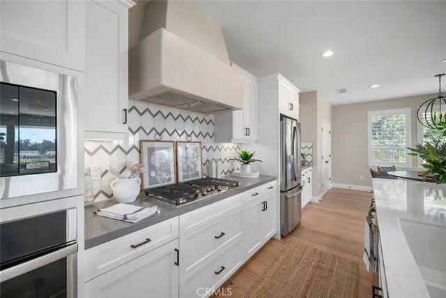 a large white kitchen with stainless steel appliances granite countertop a stove a sink and a refrigerator