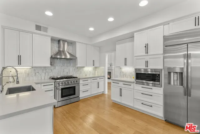 a kitchen with stainless steel appliances granite countertop a stove a sink and a refrigerator