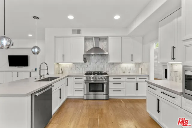 a kitchen with stainless steel appliances granite countertop a stove and white cabinets