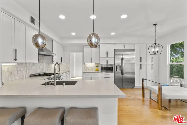 a kitchen with stainless steel appliances kitchen island granite countertop a sink a refrigerator and a coffee table