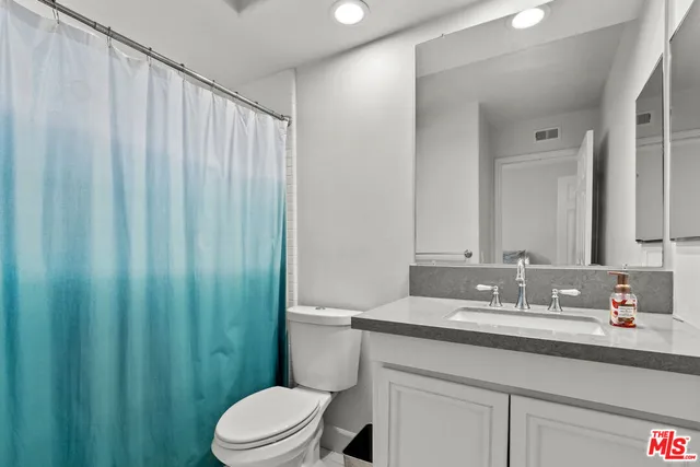 a bathroom with a granite countertop sink a toilet and a mirror