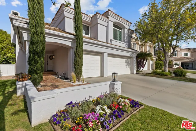a front view of house and yard with beautiful flowers and green space
