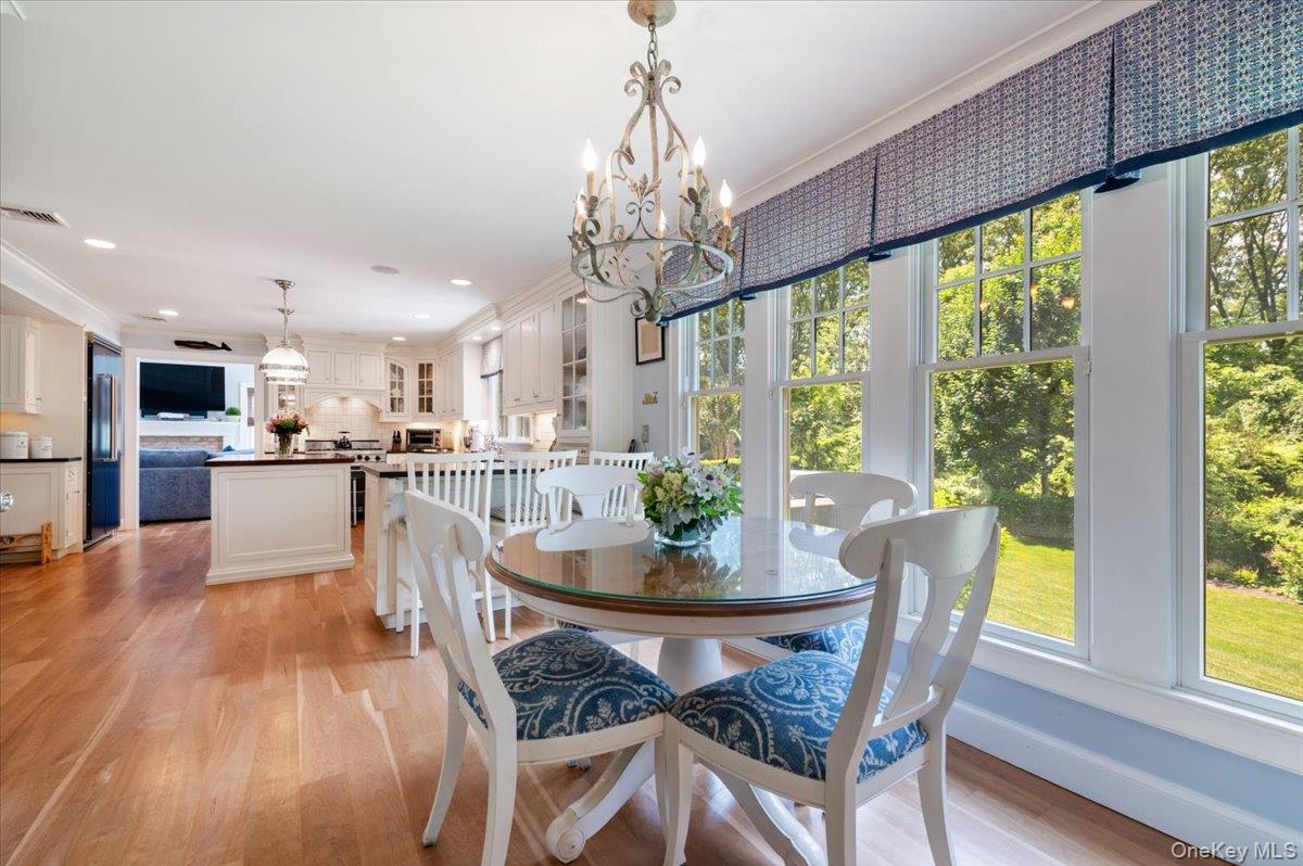 5 Fox Hunt Court Cold Spring Harbor, NY 11724 - Photo 16 of 42 Open-concept dining area featuring a round glass-top table, wood-finish flooring, and a multi-light chandelier
