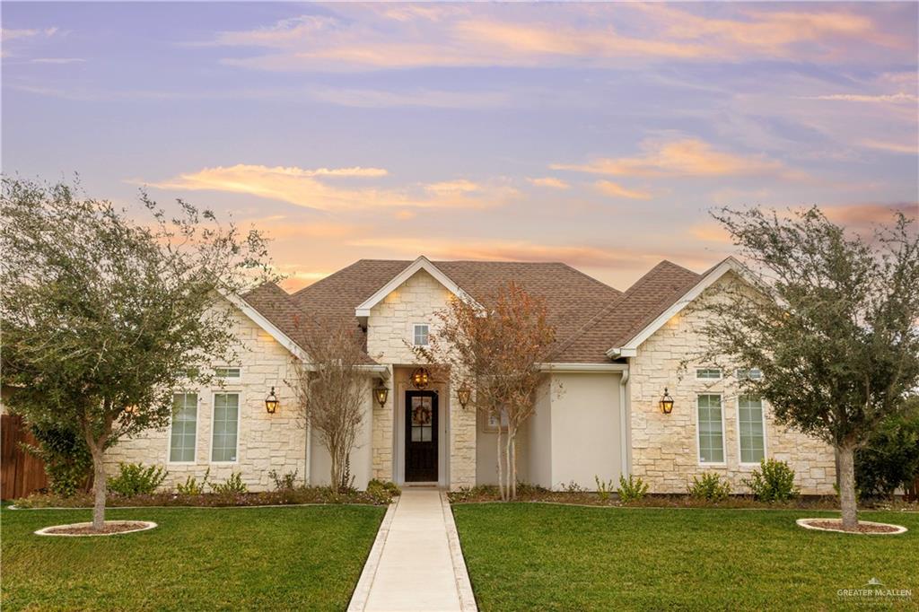 View of front facade with stone siding, a front yard, and Southern Live Oaks