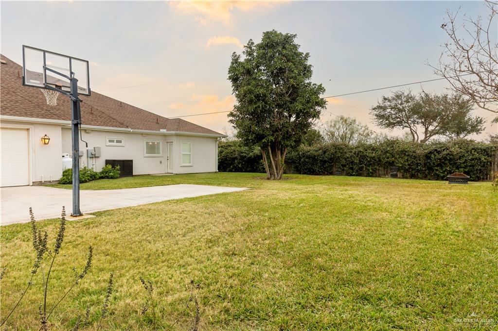 2701 Thompson Street Mission, TX 78573 - Photo 18 of 23 Yard at dusk featuring a fenced backyard, motorized gate, in-ground basketball hoop