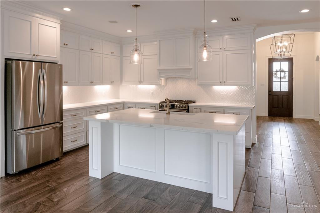 2701 Thompson Street Mission, TX 78573 - Photo 2 of 23 Kitchen with stainless steel appliances, arched walkways, wood finish floors, and white cabinetry