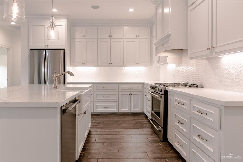 2701 Thompson Street Mission, TX 78573 - Photo 3 of 23 Kitchen with hanging light fixtures, stainless steel appliances, a center island with sink, white cabinets, and dark wood-style floors