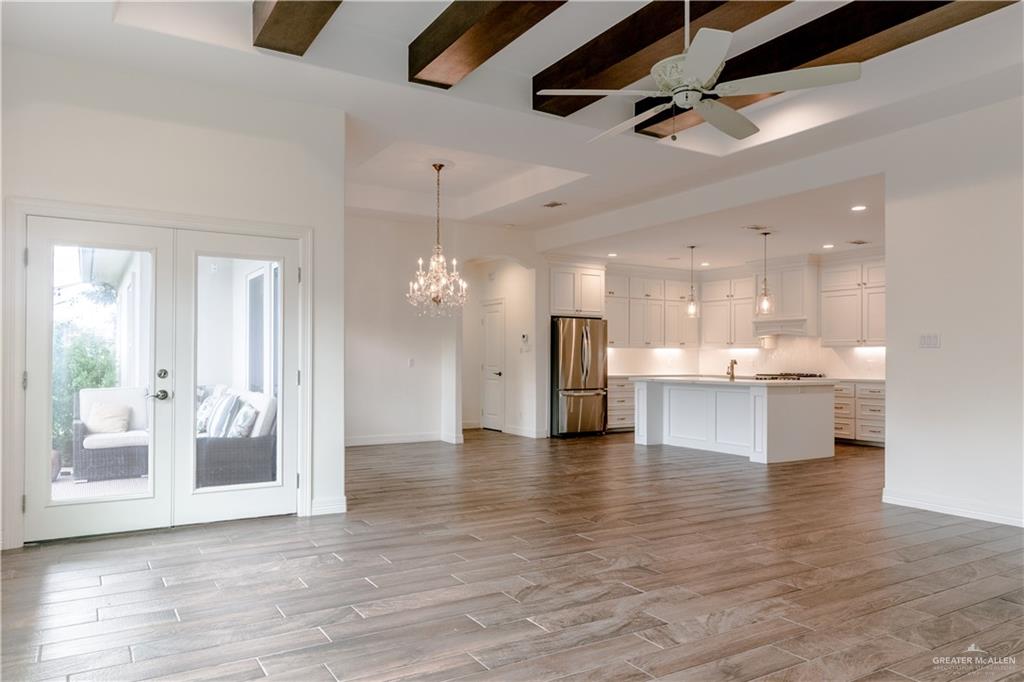 2701 Thompson Street Mission, TX 78573 - Photo 8 of 23 Unfurnished living room featuring a tray ceiling, french doors, beamed ceiling, light wood-style floors, and a ceiling fan