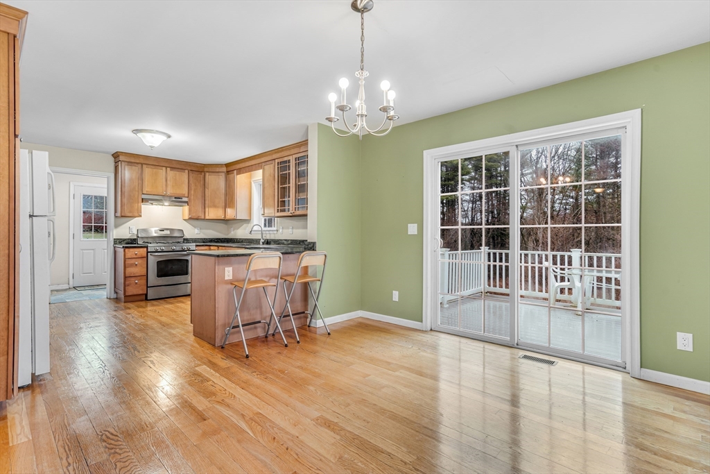 97 Packard Road Stow, MA 01775 - Photo 7 of 31 a kitchen with stainless steel appliances granite countertop a stove top oven a sink dishwasher a dining table and chairs with wooden floor