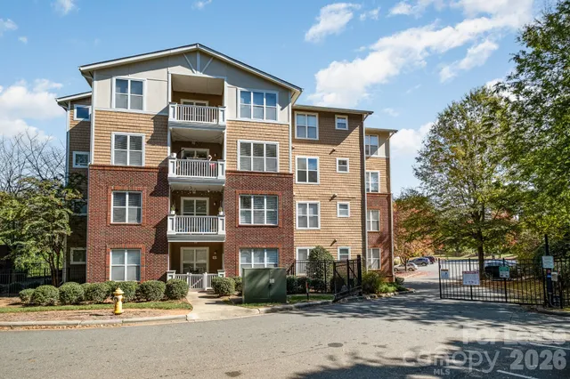 a front view of a building with lot of cars and trees